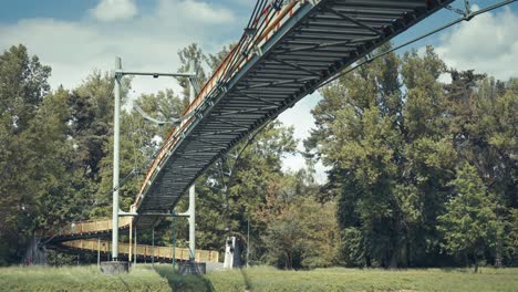 Close-up-of-a-suspension-bridge-with-steel-cables-and-wooden-planks,-set-against-a-backdrop-of-green-foliage