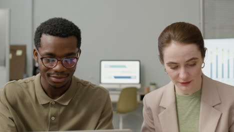 Man-And-Woman-Working-Together-Sitting-At-Desk-In-The-Office