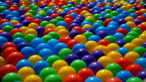 pequeñas bolas de plástico coloridas flotando y moviéndose en el agua, vista de cerca.