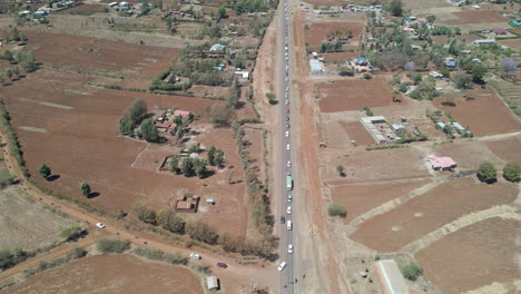 Luftaufnahme-Des-Verkehrs,-Der-Von-Einer-Autobahn-Auf-Eine-Unbefestigte-Straße-Im-Ländlichen-Kenia-Fährt