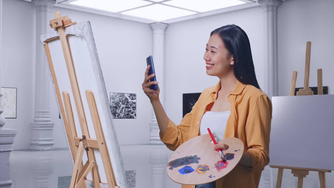 갤러리에서 오일 페인트와 으로 캔버스에 그림을 그리면서 스마트폰에서 영감을 찾는 아시아 여성 예술가