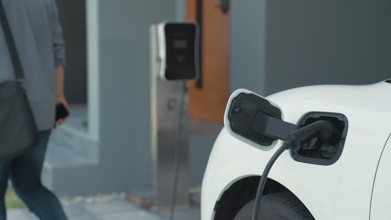Progressive man unplugs the electric vehicle's charger at his residence.