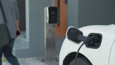 un hombre progresista desconecta el cargador del vehículo eléctrico en su residencia.