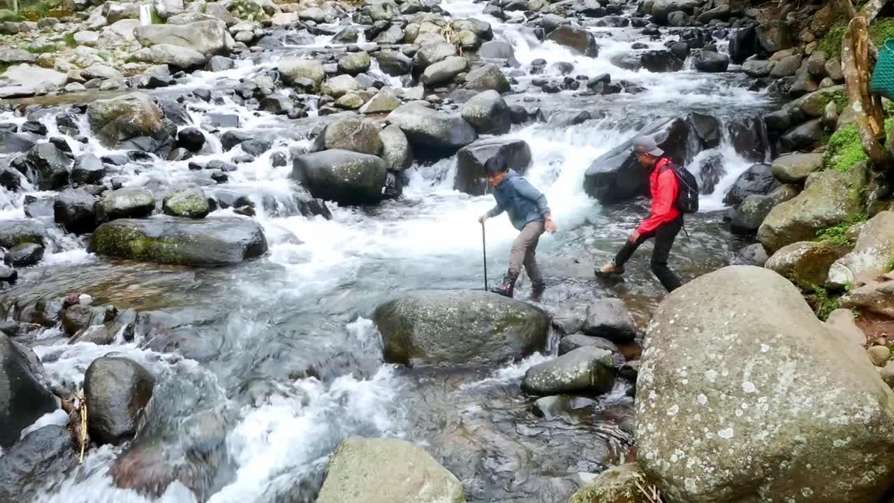 Petualang Menyeberangi Sungai Pegunungan Berarus Deras di Hutan Tropis dengan Hati-hati