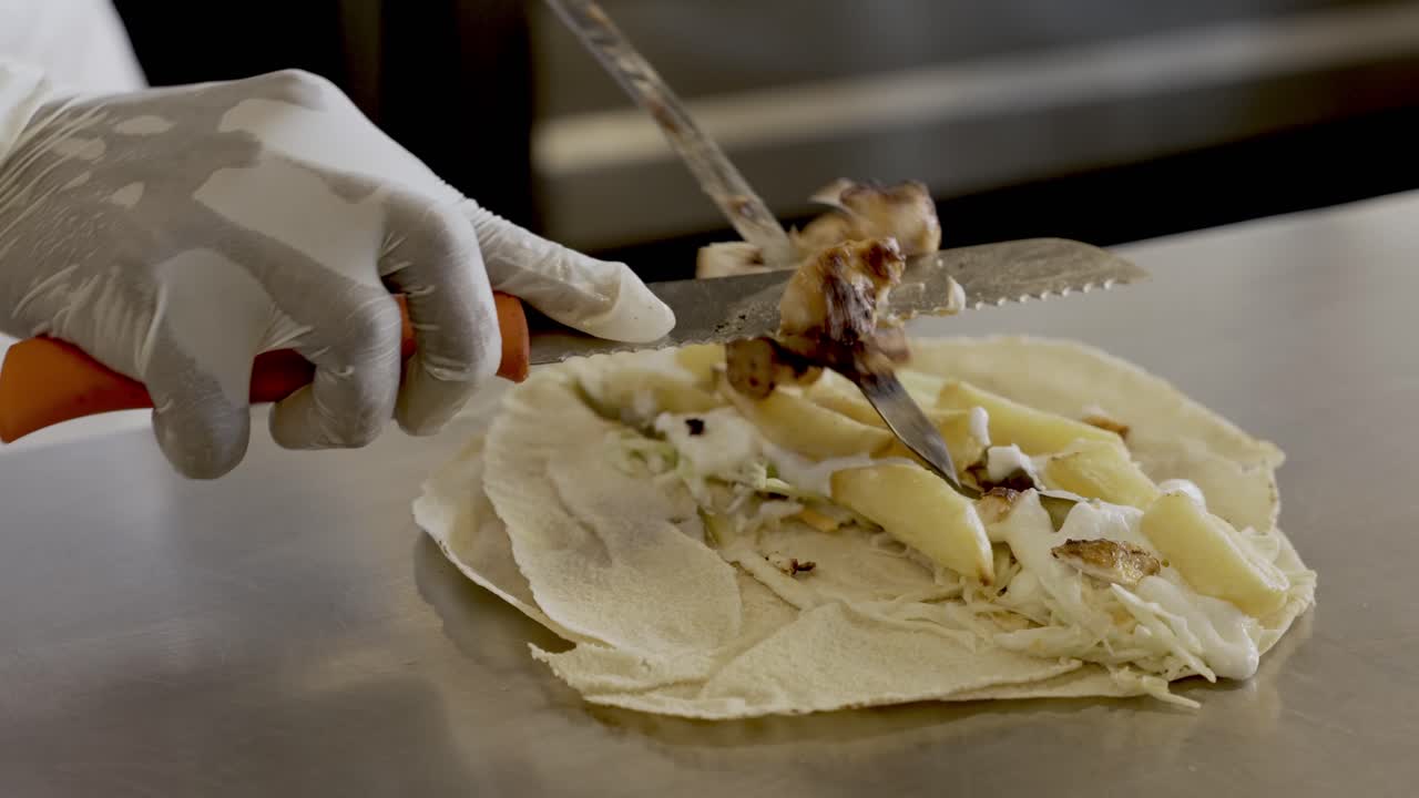 chef quitando pollo a la parrilla de la brocheta con un cuchillo sobre un sándwich
