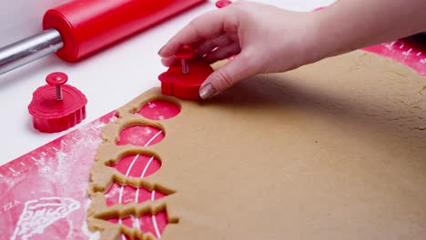 woman cutting out gingerbread dough with globe shape cutting form