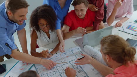 People-working-with-blueprint-in-office.-Colleagues-discussing-project-indoors.