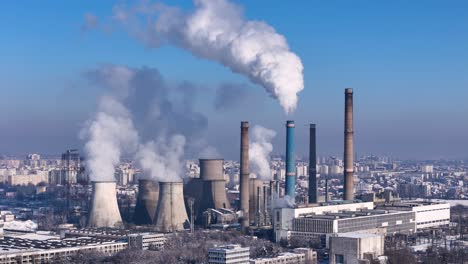 rotating drone view of a coal power plant releasing white smoke in the atmosphere with a city in the background, europe