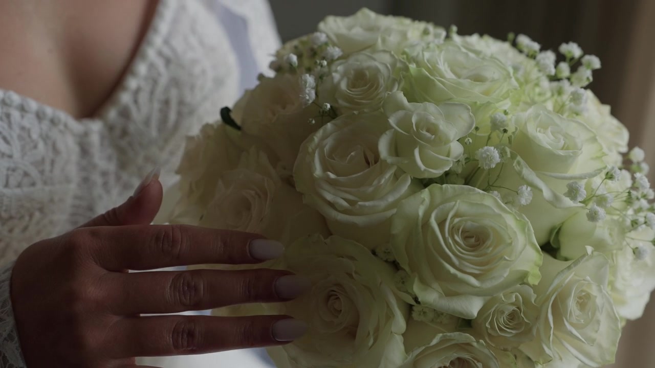 Sposa in abito di pizzo tiene un bouquet di rose bianche con la mano curata nel giorno del suo matrimonio