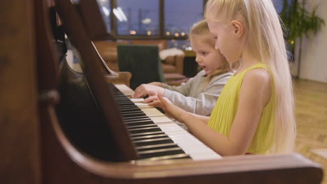 side view of two little girls playing old piano at home 4