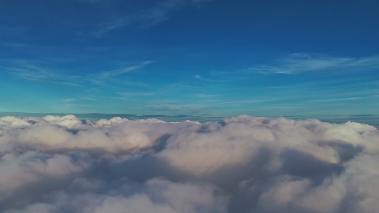 Stunning high-altitude shot soaring above a sea of dense cumulus clouds. Cinematic flight footage featuring a clear deep blue horizon, perfect for travel, heaven, and weather concepts