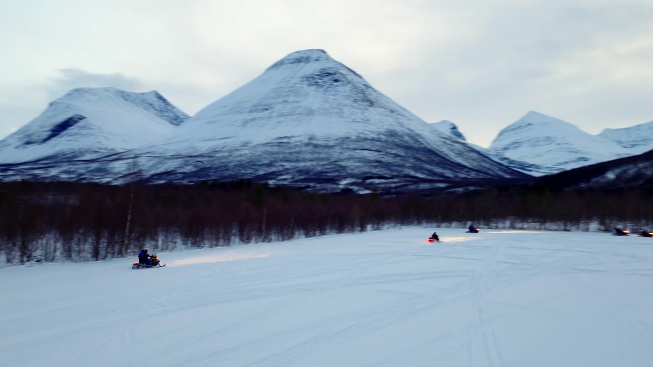Pessoa corre sobre campo nevado em expedição de ecoturismo de snowmobile, Noruega. Drone
