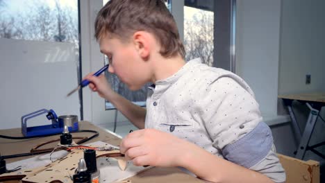 a young kid is soldering his modern flying gadget