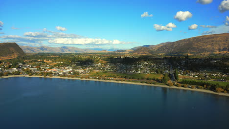 wanaka town and beach on the shore of lake wānaka, south island, new zealand at sunset - pullback aerial reveal