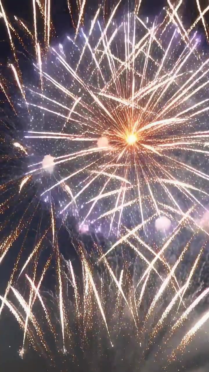 Vertikales Video: Startende Geschosse steigen nachts auf und explodieren, erzeugen goldene Explosionen und Rauch.