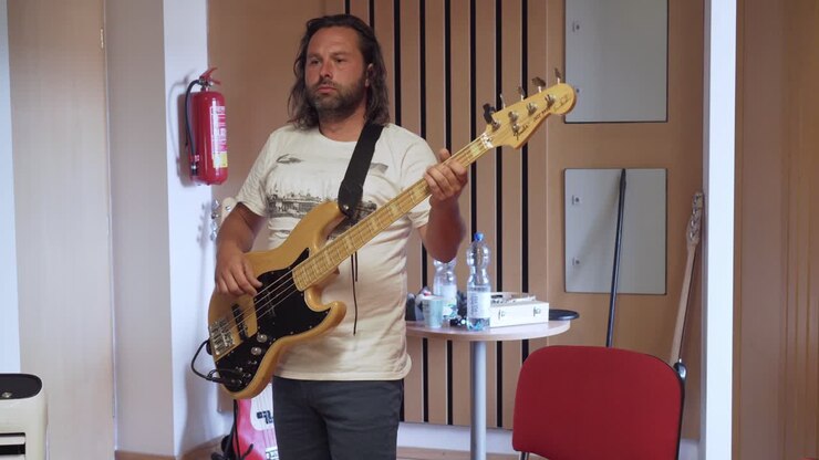 Kayıt stüdyosunda bas gitar çalan adam, orta çekim.