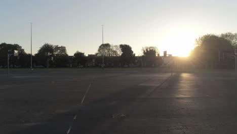 sunrise shadow silhouette empty basketball court dolly left passing net hoop