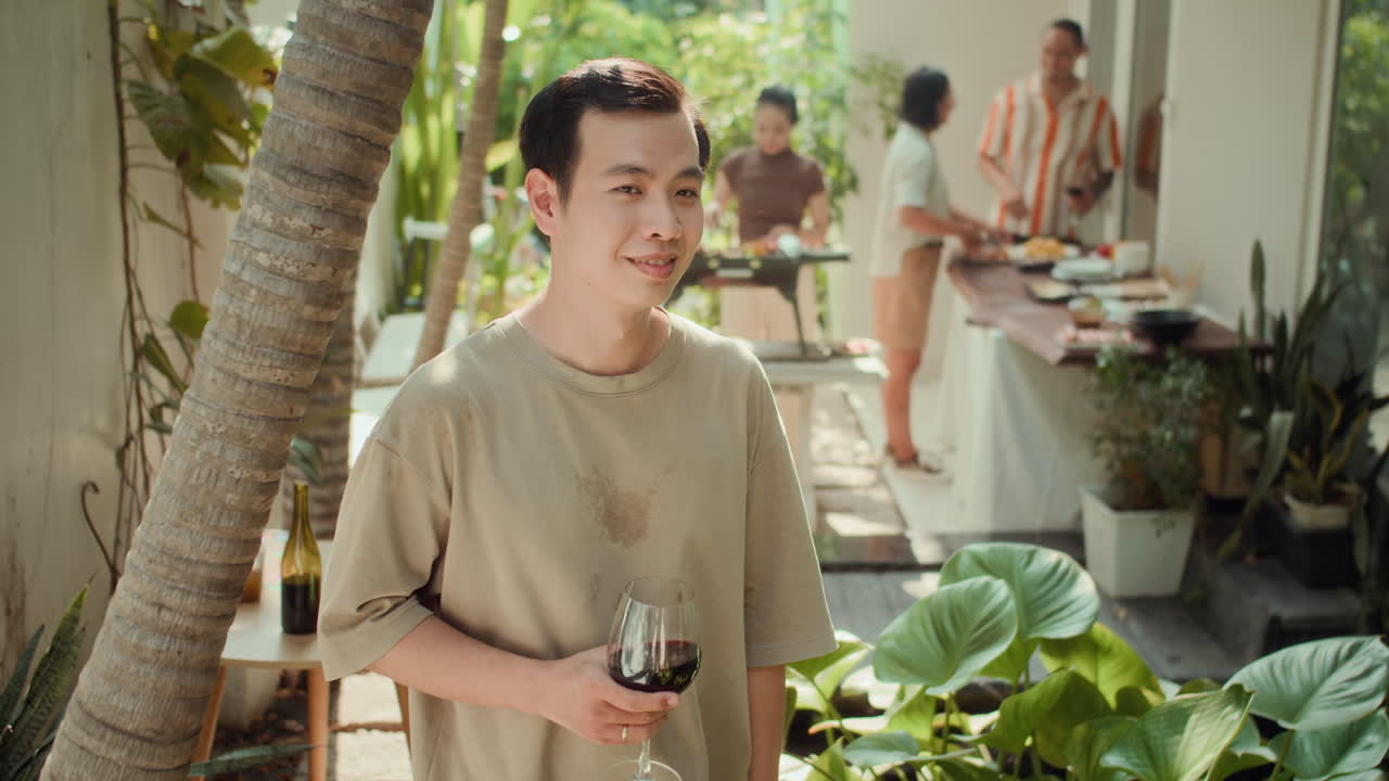 Young Man Holding Glass of Wine when Barbecuing with Friends