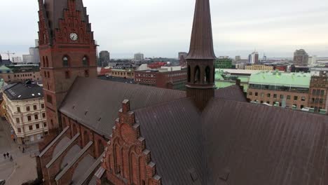 aerial drone shot flying up in front of church in malmö city. cityscape buildings in the background