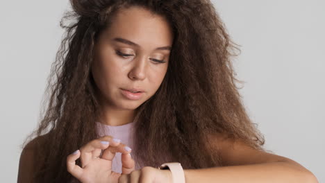 una mujer caucásica de cabello rizado revisando las notificaciones en su reloj inteligente.