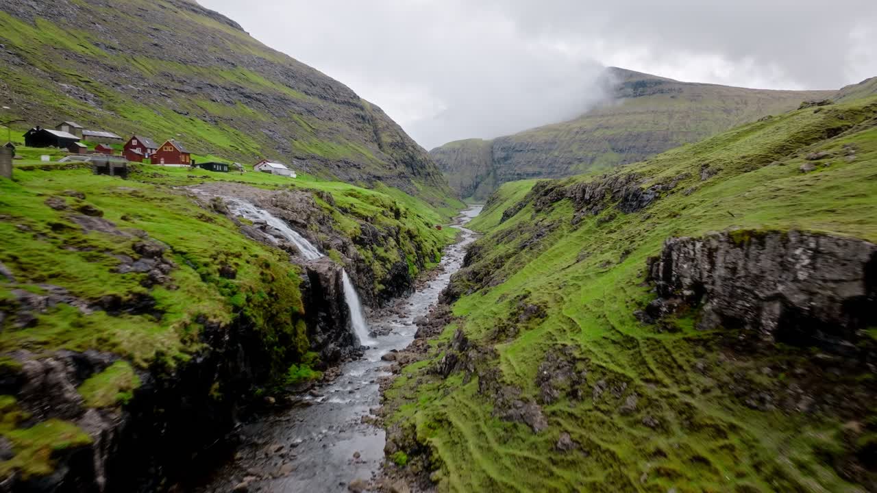 un sereno valle verde con un arroyo que fluye y montañas brumosas en las islas feroe