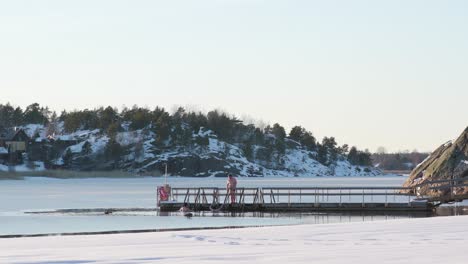 two ice swimmers getting into water on a sunny winter afternoon