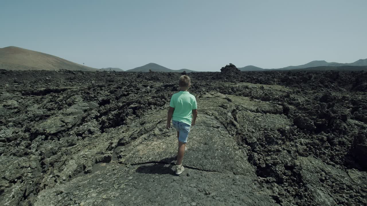 Boy traveler exploring Lanzarote unique nature and climbing lava rocks