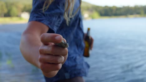 Close-up-of-man-throwing-stone-in-lake-near-lakeside-4k