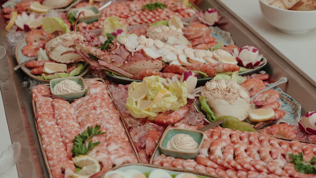 Mariscada abundante con gambas, cangrejo y salsas dispuestos sobre hielo para su presentación en un bufé