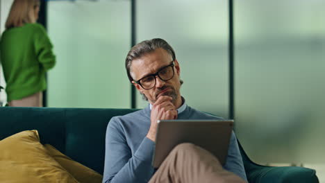 Hombre-De-Negocios-Pensativo-Mirando-La-Tableta-En-El-Primer-Plano-Del-Pasillo-De-La-Oficina.-Hombre-Trabajando-Computadora