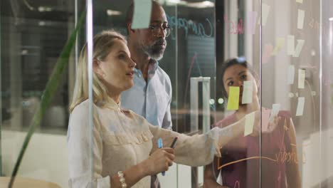 professional businesspeople discussing together over a glassboard in modern office in slow motion