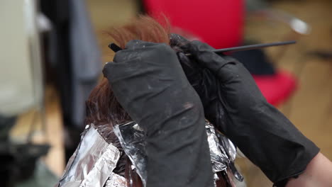 Close-up-view-of-a-professional-hairdresser-separating-strands-of-hair-before-applying-color-to-create-highlights