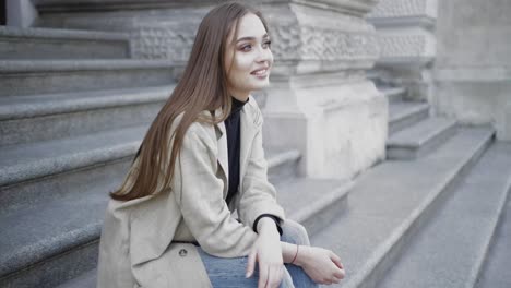 Young-stylish-female-wearing-jeans-and-coat-smiling-at-camera