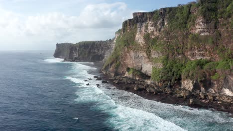 drone view of spectacular cliffs, coastline and waves in uluwatu, bali, indonesia