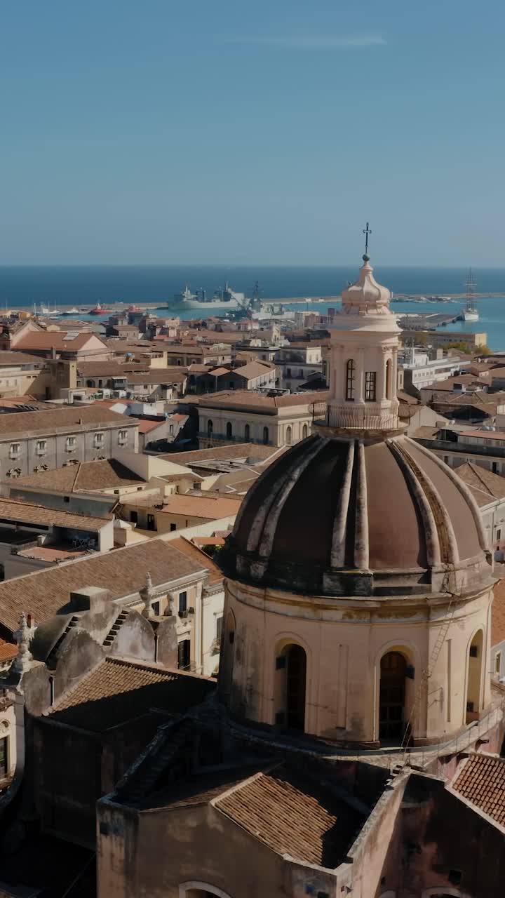 Vertical drone video of Cathedral tower in the heart of Catania old town. Historical city of Sicily. Mediterranean sea in the background. UNESCO World heritage site.