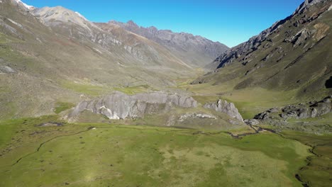 aerial approaches rock outcrop in green mountain alpine valley, peru