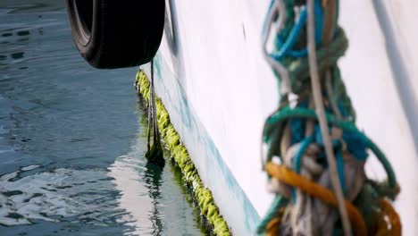 primer plano enfocado de los guardabarros de un barco amarrado que se mueve con las olas