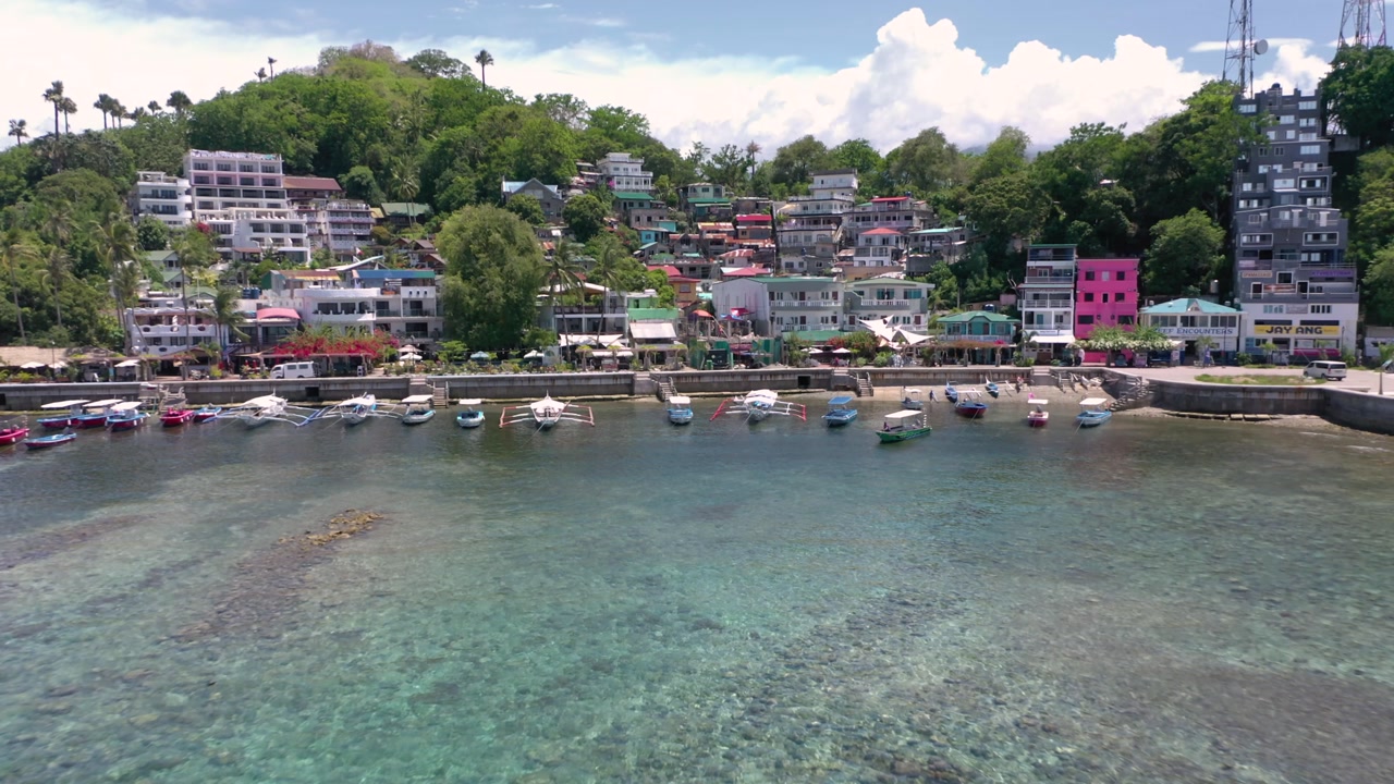 Awesome aerial of Puerto Galera and Sabang Bay with turquoise waters, boats, and diving schools, showcasing the tropical beauty of this famous Philippine destination.