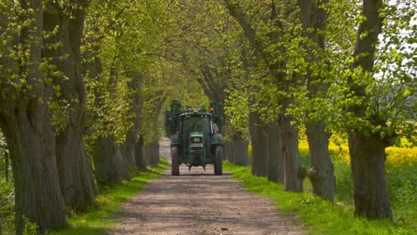 tractor with sprayer driving down wooden alley