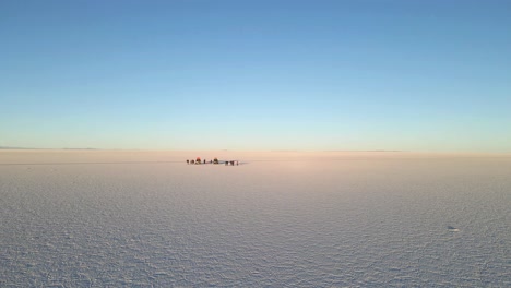 Die-Drohne-Fängt-Die-Bezaubernde-Schönheit-Der-Wüste-Von-Uyuni-Ein,-Während-Sie-Sich-In-Schnellem-Tempo-Vorwärts-Bewegt-Und-Einige-Touristen-In-Der-Wüste-Enthüllt