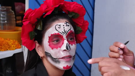 close-up: hispanic woman gets face painted for day of the dead, mexico