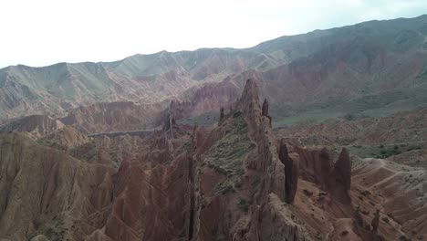 aerial approach to the towering rock formations in fairytale canyon skazka, kyrgyzstan, set against a dramatic sky