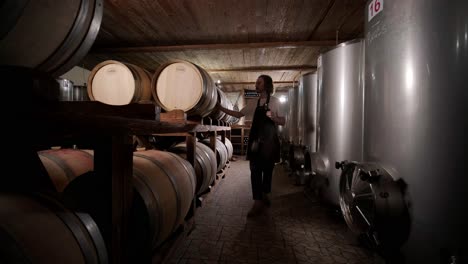 authentic shot of successful male sommelier is tasting a flavor and checking white wine quality poured in transparent glass in a wine cellar.