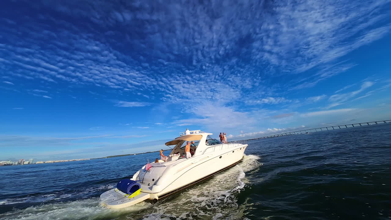 Modern motorboats sail to the different sides. FPV drone footage of the yacht at the backdrop of beautiful azure sky.