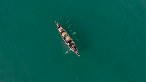 group of fishermen in a single longboat and rowing with an oar