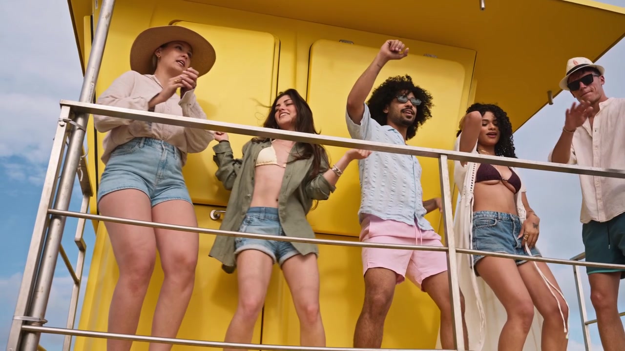 Alegre grupo de amigos bailando en una torre de salvavidas amarilla