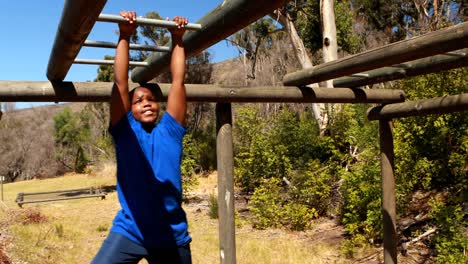 Determined-boy-exercising-on-monkey-bar-during-obstacle-course