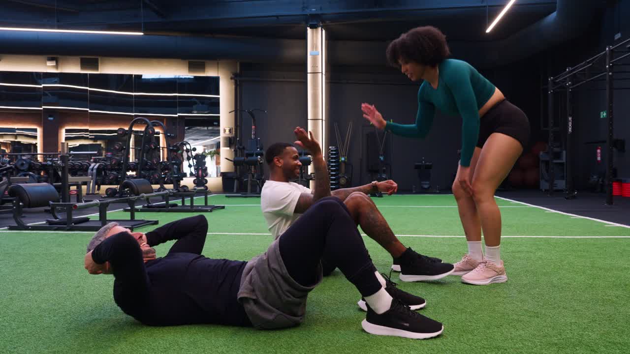 Personal Trainer motiviert Männer bei Sit-ups im Fitnessstudio