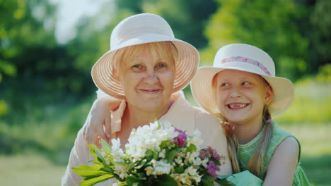 portrait of a happy elderly woman with her granddaughter hold a basket with wild flowers look at the