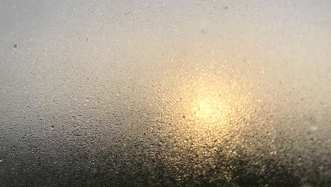 Window-glass-with-water-drops-and-blurry-sun